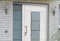 Weiße Haustür mit Glaselementen und grünem Schild daneben.