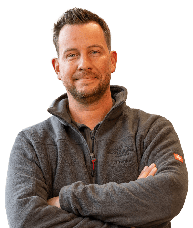 Mann mit verschränkten Armen trägt eine Fleecejacke mit Reißverschluss und Namensstickerei auf der Brust und einem Logo auf dem Ärmel