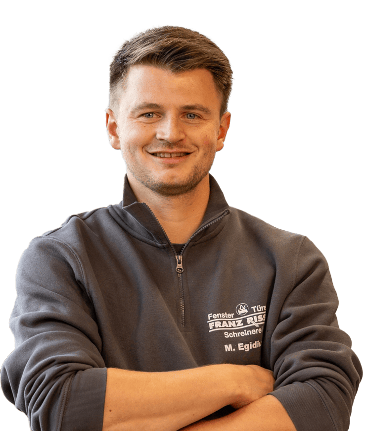 Mann mit verschränkten Armen trägt eine dunkelgraue Arbeitsjacke mit Reißverschluss und Firmenlogo auf der Brust